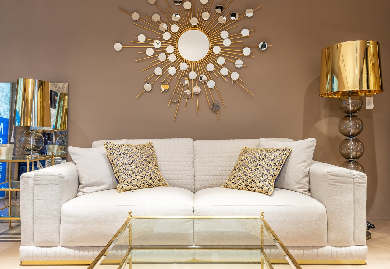 A contemporary living room featuring a stylish sofa with gold decor elements and a sunburst wall mirror.